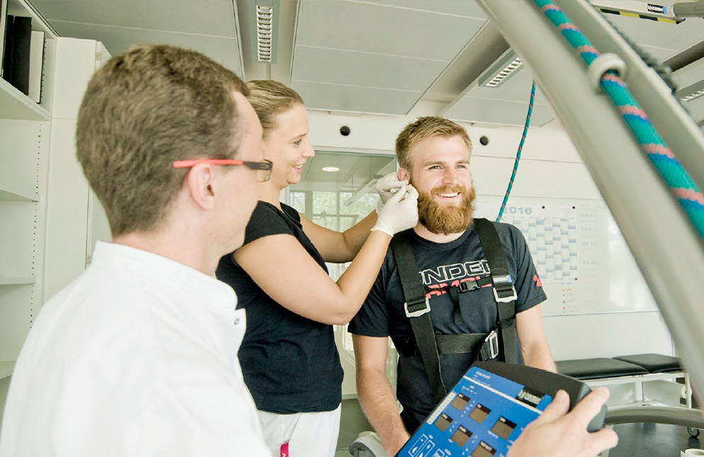 Sportler auf dem Laufband zur Laktatdignostik mit Blutabnahme am Ohrläppchen